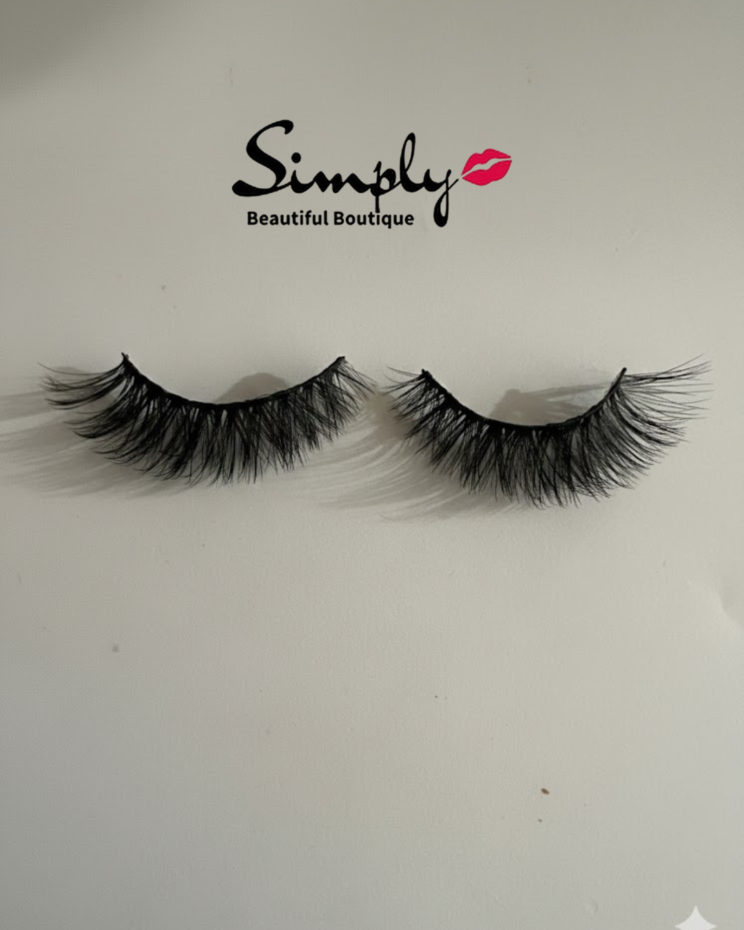 Flirty Glam Strip Lashes. Pair of false eyelashes with 'Simply Beautiful Boutique' logo on a light gray background